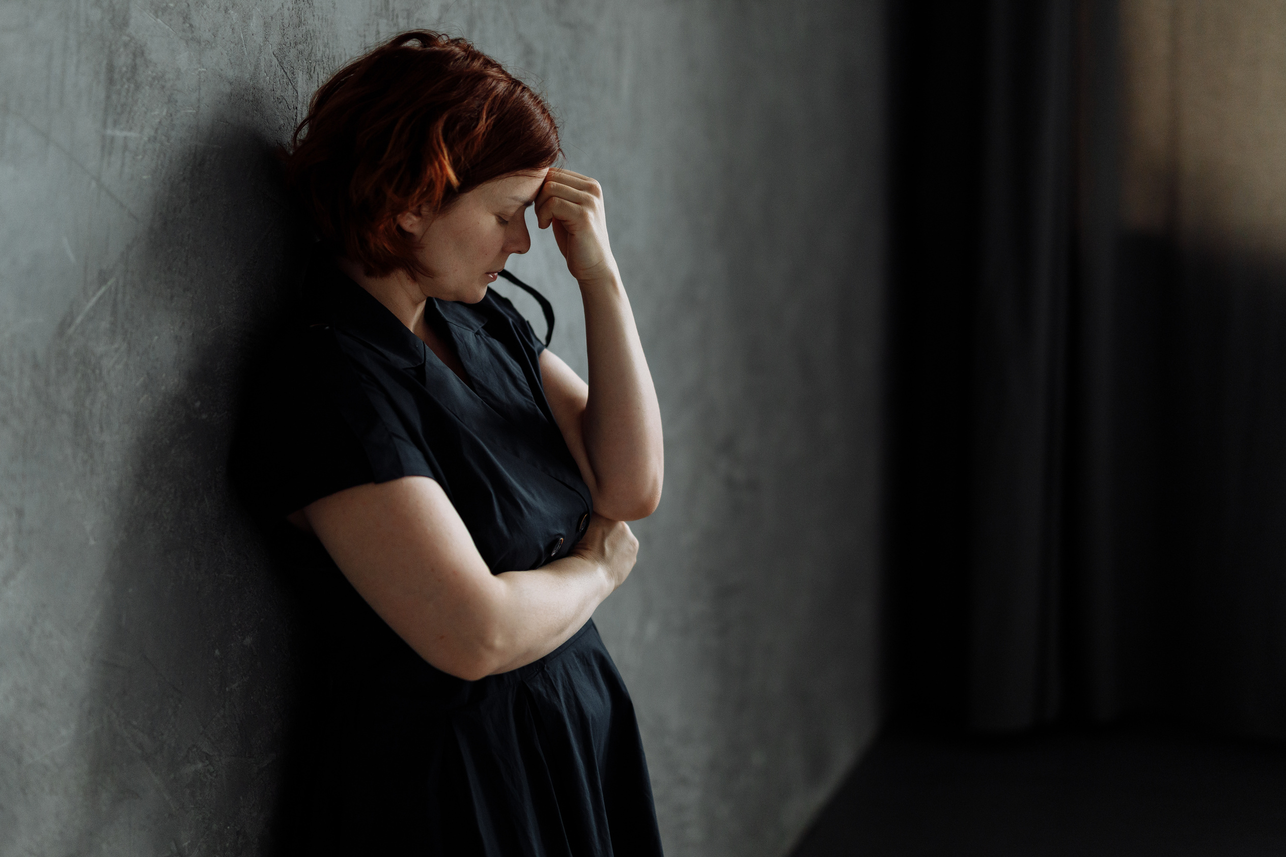 A Depressed Woman Leaning on a Concrete Wall